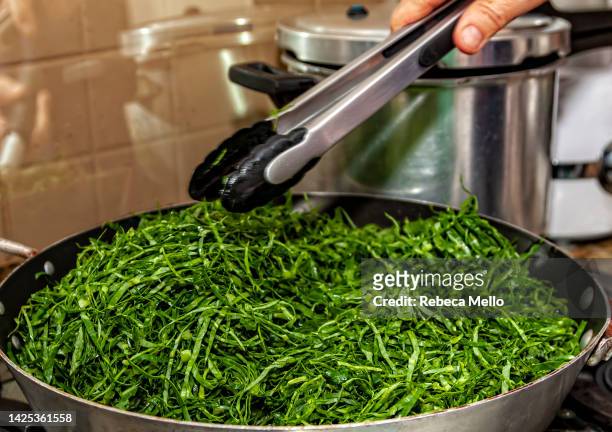 the kale is being sautéed in the skillet. - feijoada stock pictures, royalty-free photos & images