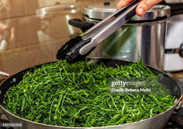 the kale is being sautéed in the skillet. - feijoada 個照片及圖片檔