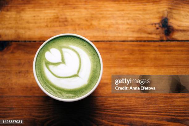 matcha green tea latte with foam art in ceramic cup on the wooden table. backdrop for your design with copy space. photography from above - tea cup overhead view photos et images de collection