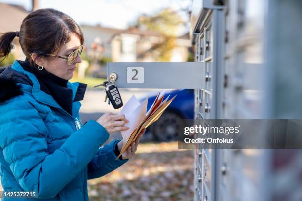 woman collecting post at home at the mailbox in autumn, quebec, canada - debt collector stockfoto's en -beelden