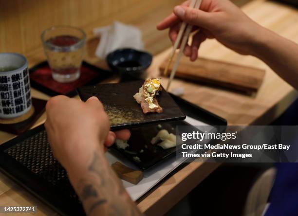 Golden State Warriors rookie Ryan Rollins, right, samples some sushi with edible gold leaf after learning how to make rolls from chef Gary Hong at...