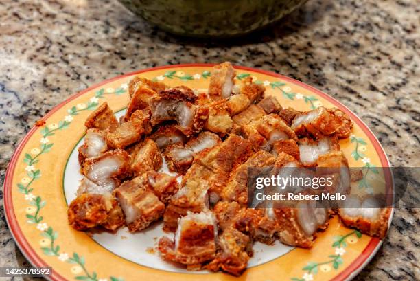 viewed from above. plate with crackling, fried pieces of pork skin, a very popular side dish in brazilian feijoada. - brazilian feijoada dish stock-fotos und bilder