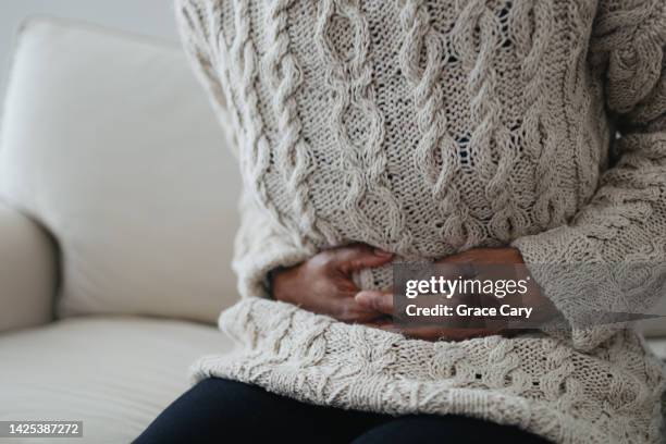 woman holds abdomen in pain - fibroids stock pictures, royalty-free photos & images