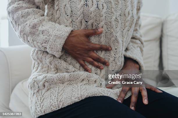 woman holds abdomen in pain - woman holding tummy bildbanksfoton och bilder