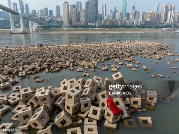 Woman stands on concrete breakwater blocks which are exposed along the Yangtze River on September 19, 2022 in Chongqing, China. The water level of...