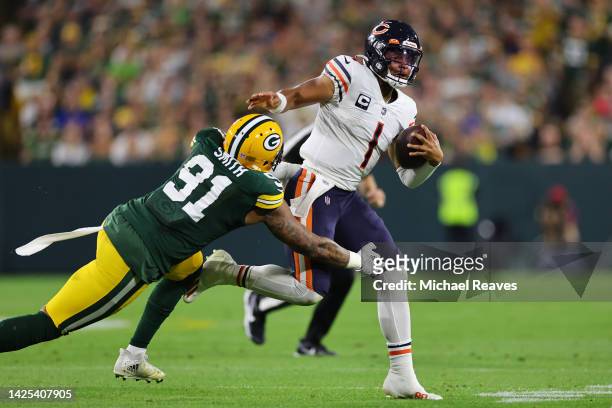 Justin Fields of the Chicago Bears breaks a tackle from Preston Smith of the Green Bay Packers at Lambeau Field on September 18, 2022 in Green Bay,...