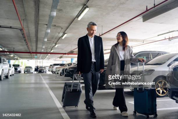 business people traveling for business drag luggage and chat in the airport parking lot. - parking lot stockfoto's en -beelden
