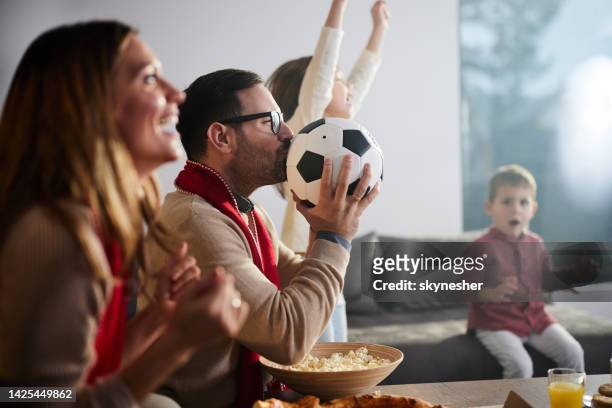 fröhliche familie, die fußballspiel zu hause im fernsehen sieht. - mens world championship stock-fotos und bilder