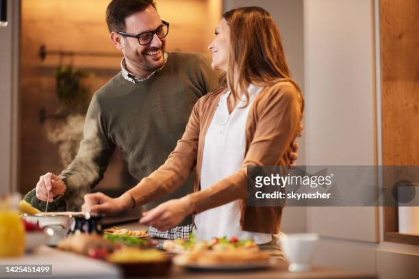 happy couple preparing food and drinks in the kitchen. - making a sandwich stockfoto's en -beelden