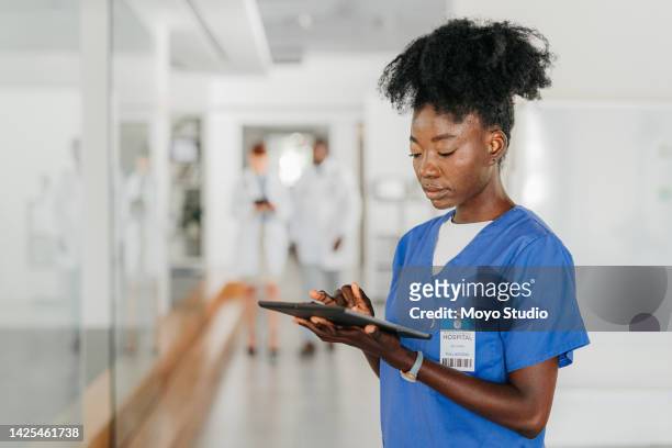 healthcare woman, working on tablet, in medical building doctors walk, in blurred background. young african nurse, at work in hospital or clinic, in communication or doing research via the internet. - ipad white background stock pictures, royalty-free photos & images