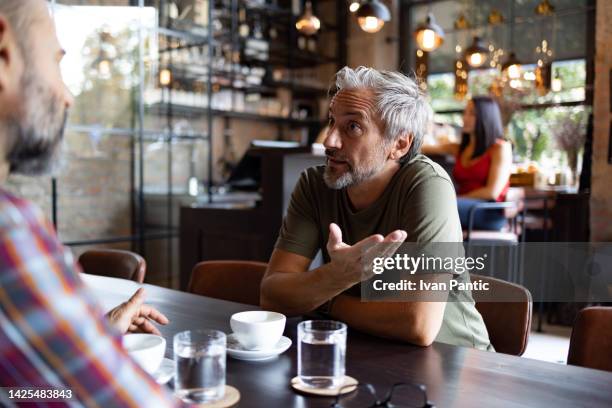 two friends meeting for a cup of coffee - male friendship stock pictures, royalty-free photos & images