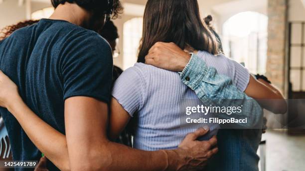 personas que se abrazan juntas en su oficina - abrazo fotografías e imágenes de stock