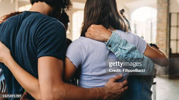 people embracing together in their office - omarmd stockfoto's en -beelden