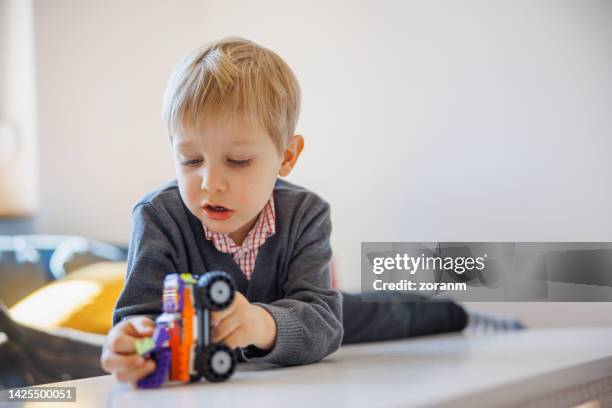 blond toddler playing with toy cars on the living room table - boy playing with cars stock pictures, royalty-free photos & images