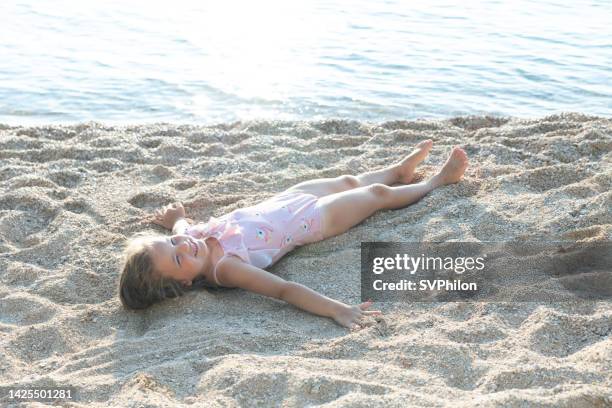 the little girl lies on the beach next to the sea. - croatia girls stock pictures, royalty-free photos & images