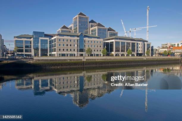 'george's quay' reflected in the river liffey in dublin - dublin city skyline stock-fotos und bilder