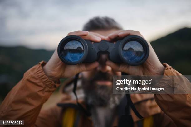 portrait of man looking trough binoculars. - verrekijker stockfoto's en -beelden