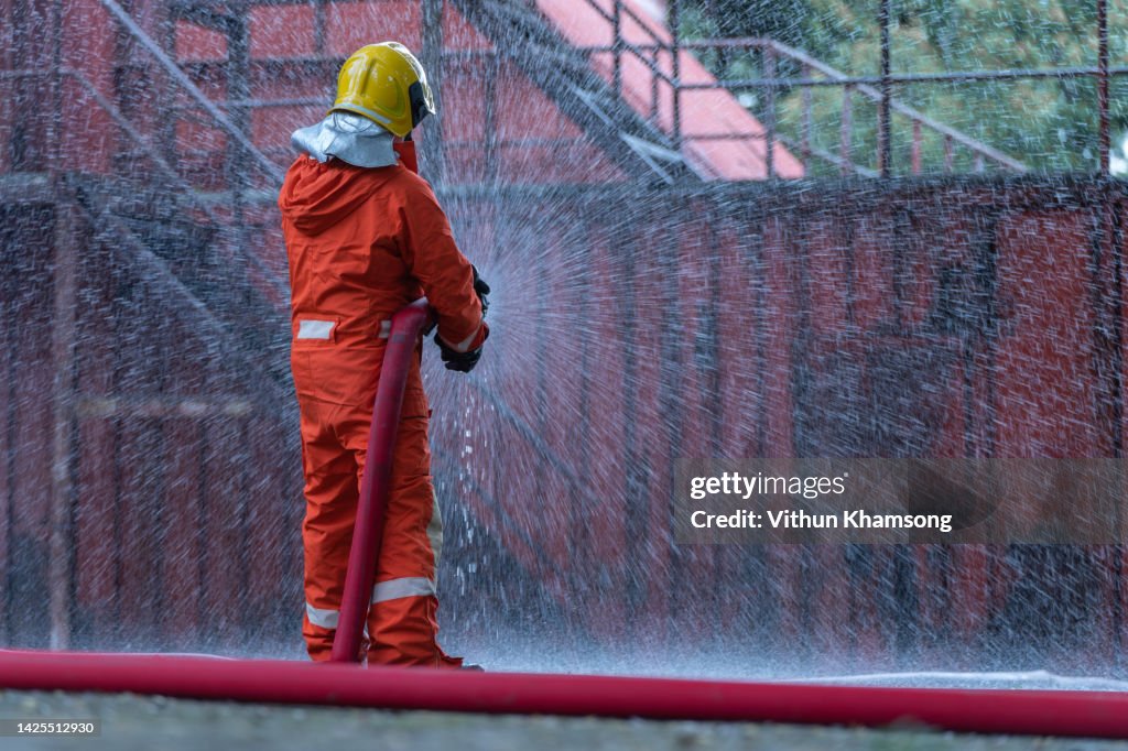 Fireman using water extinguishing a burning house fire with on emergency situation.