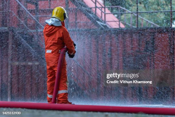 fireman using water extinguishing a burning house fire with on emergency situation. - feuerwehrschlauch stock-fotos und bilder