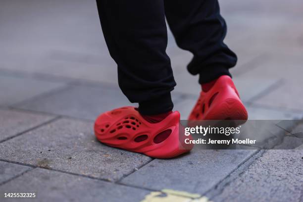 Fashion week guest seen wearing red adidas yeezy shoes, outside paul and joe during London Fashion Week September 2022 on September 17, 2022 in...