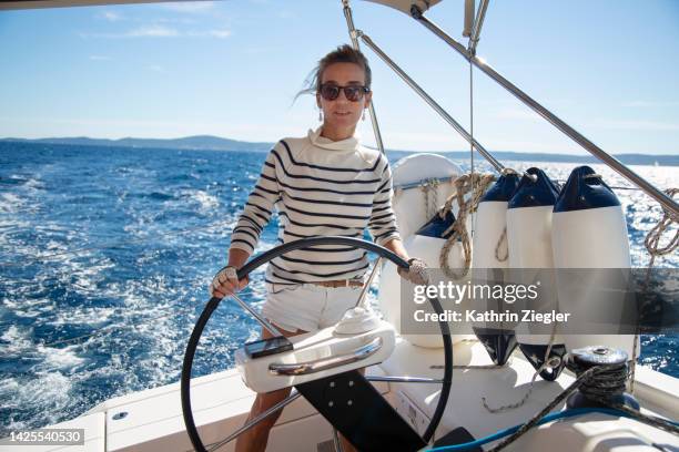 female crew member steering yacht - zeemansstrepen stockfoto's en -beelden