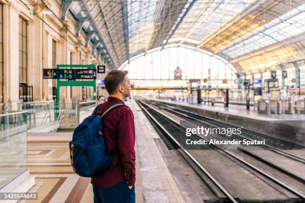 man waiting for a train at the train station, side view - francia fotografías e imágenes de stock