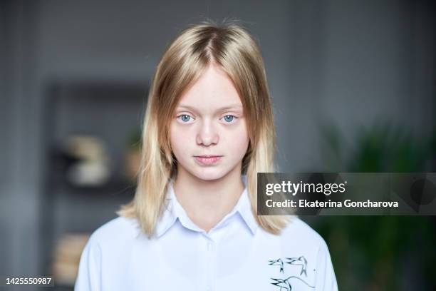 portrait of a 13-year-old girl with blond hair and blue eyes looking into the camera - 12 year old blonde girl stock-fotos und bilder