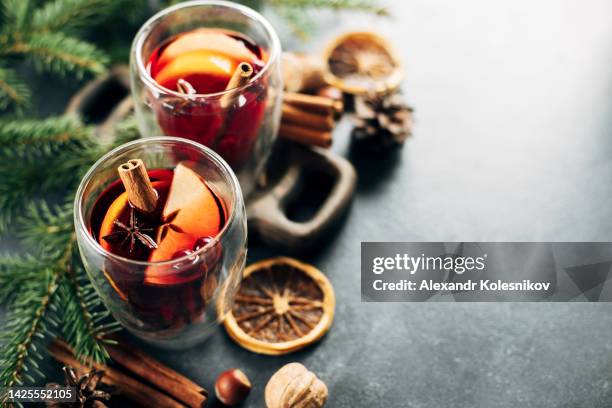 glass of mulled wine with slice of orange, apple, anise and cinnamon stick with fir tree branch on background. copy space - ホットワイン ストックフォトと画像