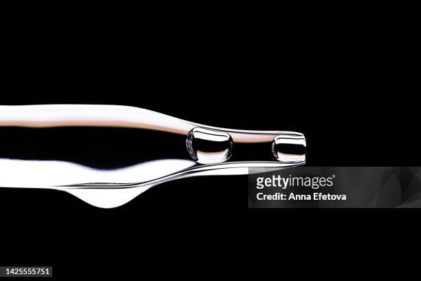 drop of serum falls from glass pipette on black background. cosmetic liquid based on polyglutamic acid, ceramides and essential oils. macro photography - oil macro stock pictures, royalty-free photos & images