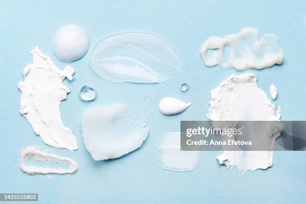 set of cosmetic smears applied on blue background. cleansing foam, lotions, scrubs, gels and moisturizing creams. beauty products with ceramides, polyglutamic acid and beneficial oils. flat lay style - foam material stockfoto's en -beelden