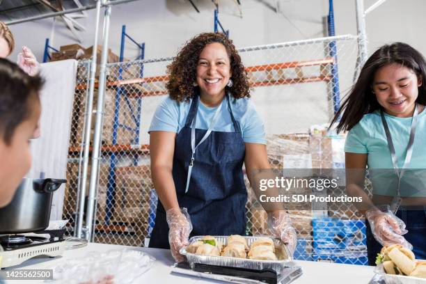 female volunteer smiles for the camera - homeless shelter stock pictures, royalty-free photos & images