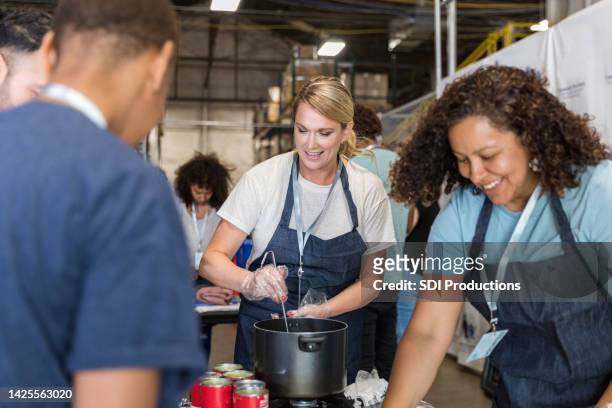 multiracial volunteer group prepares meals for soup kitchen - human arm stockfoto's en -beelden