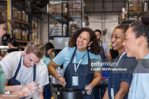 frauen lächeln und unterhalten sich, während sie essen für die suppenküche zubereiten - smile woman child stock-fotos und bilder