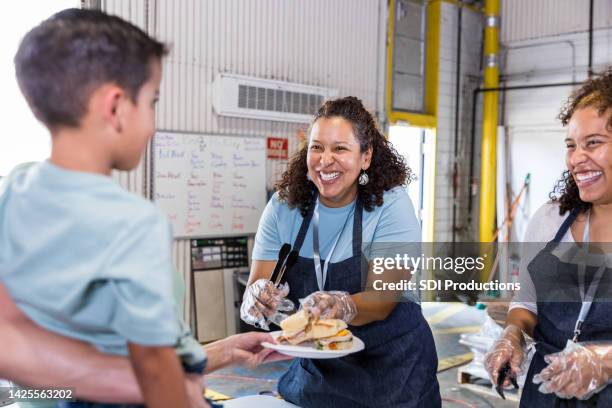 woman smiles while serving young food bank client - american influencer stock pictures, royalty-free photos & images
