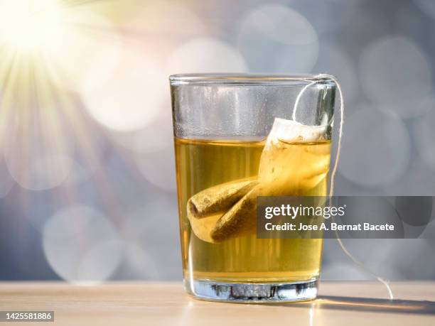 glass cup with a hot infusion of herbs illuminated by sunlight. - sachet stockfoto's en -beelden