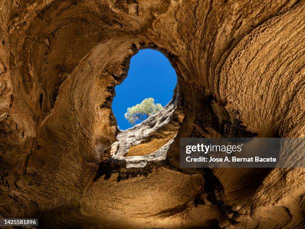 interior of a large cave with a hole in the ceiling through which sunlight enters. - innere ruhe und blau stock-fotos und bilder