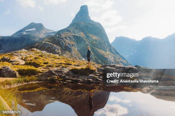 side view of a man backpacker hiking in the mountains by the lake in norway during sunny day - romsdal in norway stockfoto's en -beelden