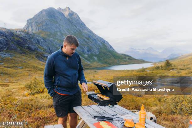 male admiring autumn in the mountains and cooking the camping dinner in norway - bbq avocado imagens e fotografias de stock