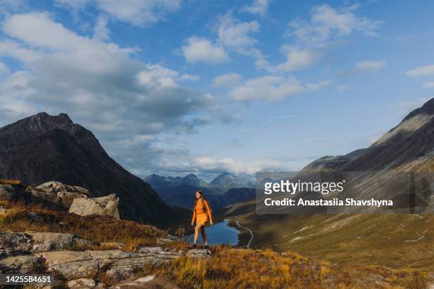woman hiker contemplating the scenic mountain landscape during autumn time in norway - alesund noorwegen stock pictures, royalty-free photos & images