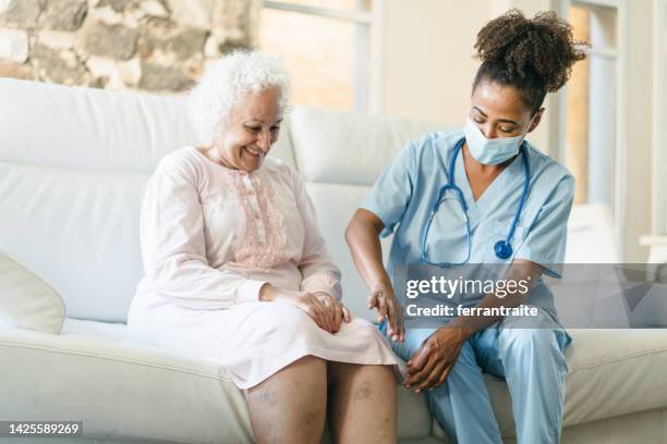 ältere frau, die zu hause eine physiotherapeutische behandlung erhält - krampfader stock-fotos und bilder