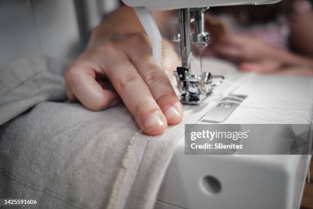 female fashion designer hands using sewing machine - zoom in stockfoto's en -beelden