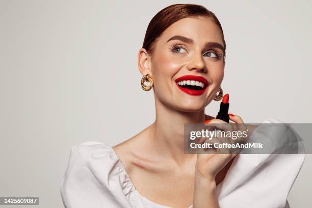 beautiful emotional woman with bright make-up applying red lipstick - lipstick imagens e fotografias de stock