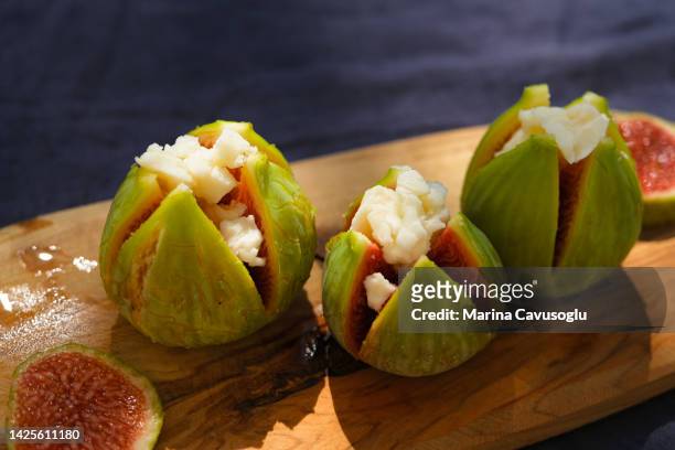 fresh green figs with goat cheese on wooden cutting board. vegetarian hors d'oeuvre or antipasto. - sugarfree stock pictures, royalty-free photos & images