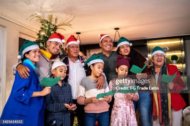 family together singing christmas carols at home - cousins stockfoto's en -beelden