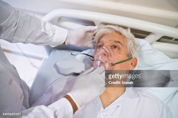 médico ajusta máscara de oxigênio de paciente no hospital - oxygen mask - fotografias e filmes do acervo