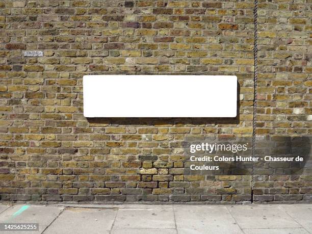 empty street name sign on a weathered brick wall and sidewalk in london, england, uk - street name sign fotografías e imágenes de stock