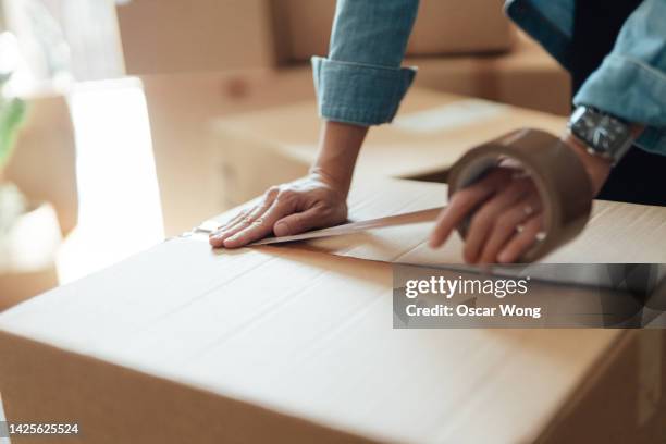 close-up of female hand packing cardboard boxes - possession stock pictures, royalty-free photos & images
