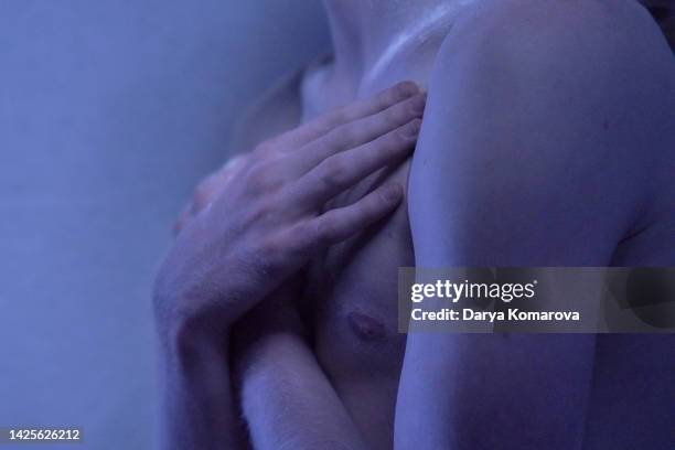 close up of hands of young albino man on dark background. a man without a t-shirt. the arms are crossed on the chest.  the concept of problem skin, cosmetics for sensitive skin, acne and sun protection. - body men close up stock-fotos und bilder