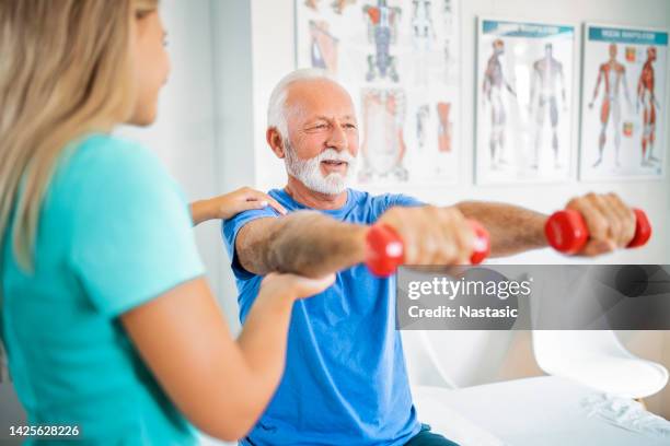 senior man on a manual therapy treatment holding dumbbell - osteoporosis stock pictures, royalty-free photos & images