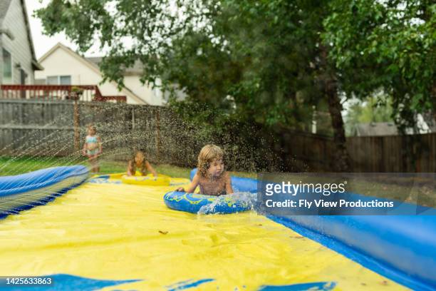 group of ethnic children enjoying summer and sunshine! - backyard water slide stock pictures, royalty-free photos & images